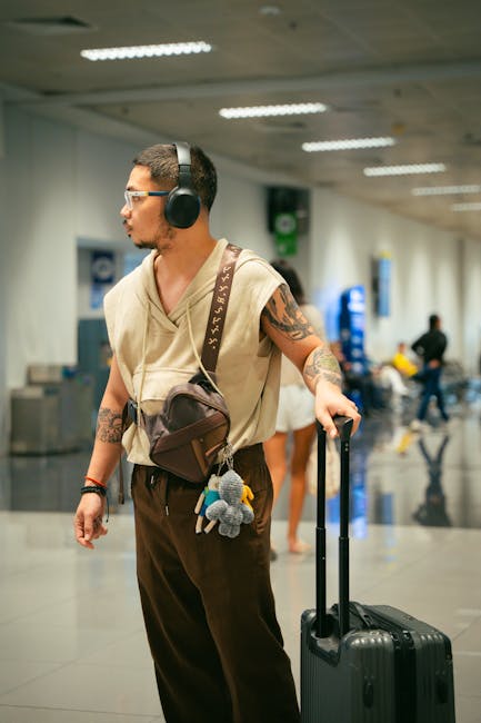 Traveler wearing wireless headphones near luggage at an airport terminal