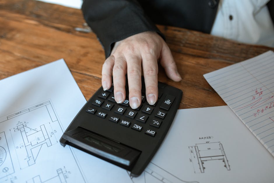 Person calculating equipment rental total costs using checklist and calculator