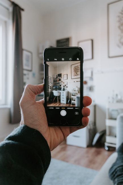 Person holding a smartphone and capturing a photo in a bright street scene