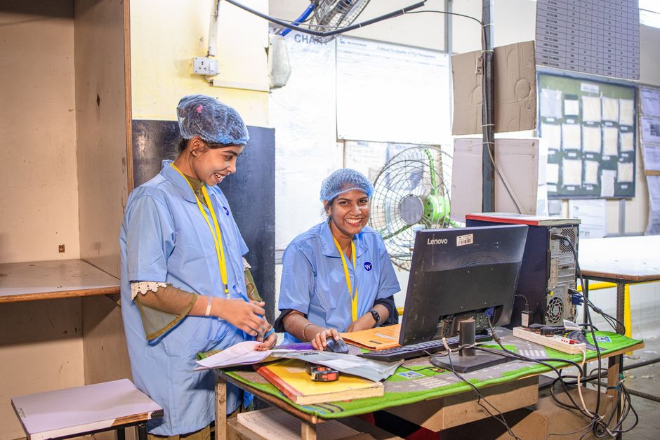 Technician inspecting an electronic circuit board in a manufacturing setting with testing equipment