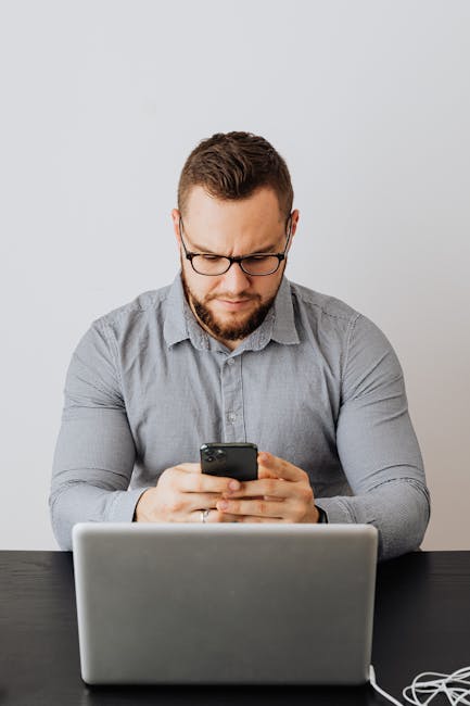 Hand holding a phone showing a suspicious phishing-style email message